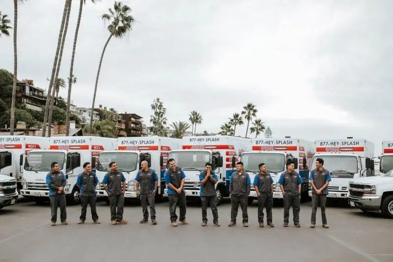 Team photo in front of service vehicles on california beach